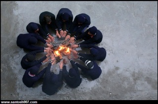 School boys siting around fire in Winter